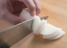 大根の丸みのあるほうを手前にしてまな板に置き、大根を片方の指で押さえ固定する。包丁の刃先で、端から均一の厚さに切る。