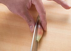 親指と人差し指でみょうがをつまむようにして押さえ、包丁の刃先で縦半分に切る。