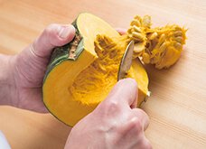 かぼちゃを繊維にそって4等分に切り、スプーンで種とわたをかき出して取り除く。