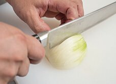 縦に均等な切り目を入れる。玉ねぎの根元が手前の時は包丁の刃元で、逆に向こう側の時は包丁の刃先を使う。切りやすい向きでOK。
