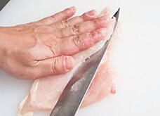 厚みのある赤身に手をあてて押さえ、包丁を寝かせ、肉の厚みが半分になるように切り込みを入れ、開く。