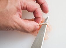 筋の先端部分（1cm位）に包丁で切り目をいれ、筋の先を指でつまみやすくする。