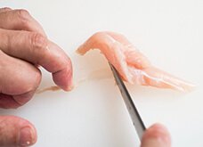 肉を裏返し、筋を指で押さえる。包丁の切っ先を筋の上に置き、ささみの身の方向へ滑らせるように動かし、筋を抜く。