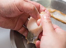 次に黒いウロ（中腸線）、エラ、卵巣（オレンジ）や白子（白）を貝柱から取り外す。