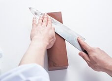 支える手の指を置いた部分しか研げないので、次に研いだ場所の少し下を研ぎ石の上に置き、支える手の指でその上を押さえる。