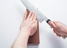 包丁の刃元の面が研ぎ石に当たるように包丁を持つ手を少し持ち上げ、包丁に少し角度をつけて、斜め上下に滑らせる。